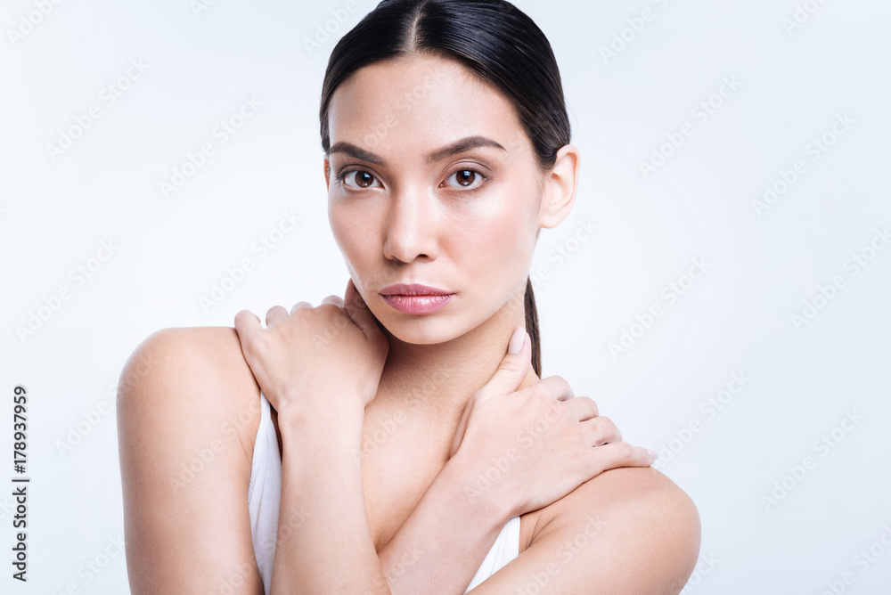 Charming brunette crossing her arms and holding hands near neck