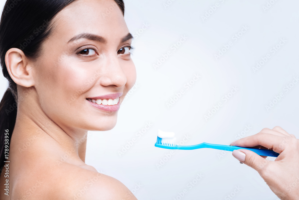 Cheerful woman smiling while being about to brush her teeth Cheerful woman smiling while being about to brush her teeth