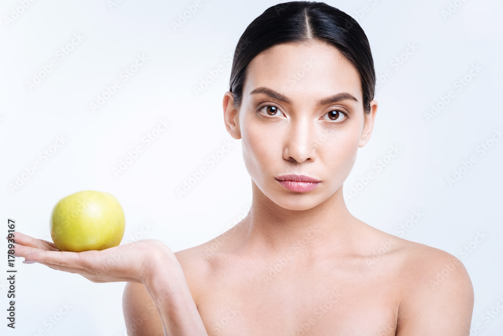 Pleasant woman holding apple on her palm