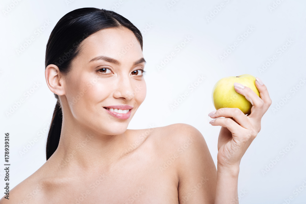 Smiling woman posing with a yellow apple in hands Smiling woman posing with a yellow apple in hands
