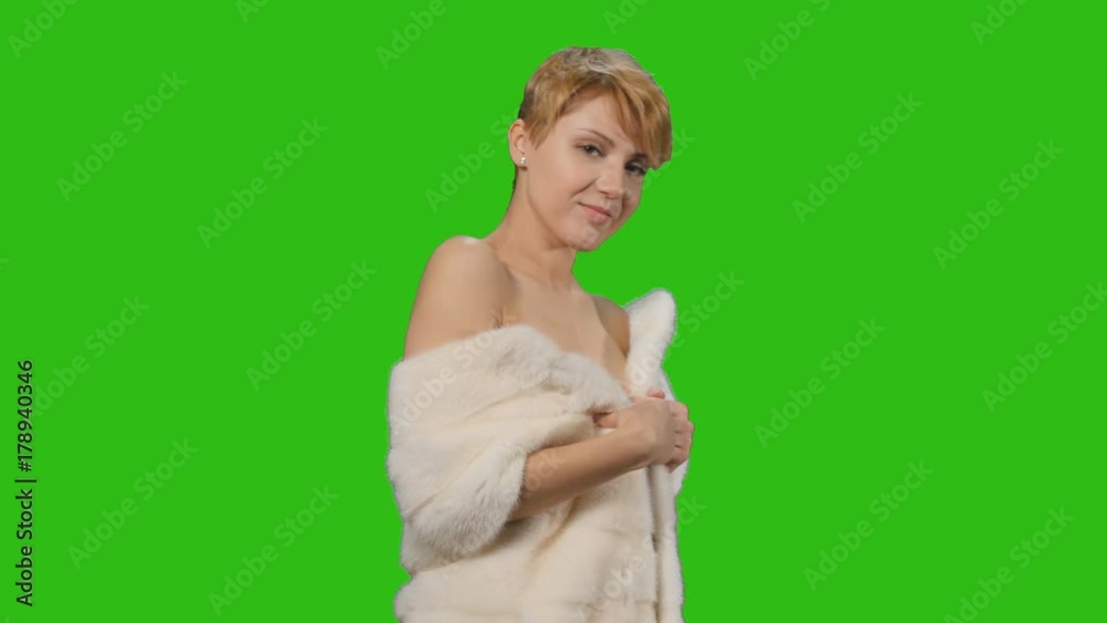 Beautiful model in fur cape poses for camera at chroma key background Beautiful model in fur cape poses for camera at chroma key background