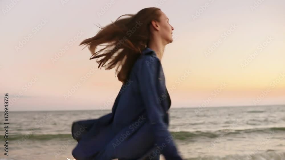 Young beautiful woman running by the sea during sunset and holding burning sparkling candles in both hands. Slowmotion shot Young beautiful woman running by the sea during sunset and holding burning sparkling candles in both hands. Slowmotion shot