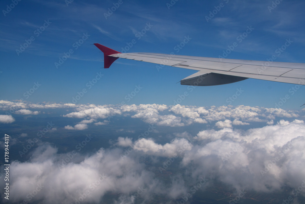 View of the clouds from the airplane window with visible wing View of the clouds from the airplane window with visible wing