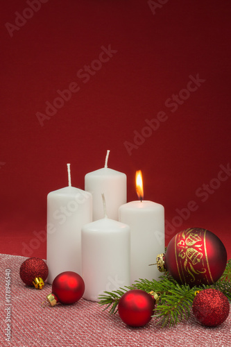 white candles with red christmas baubles on red background
