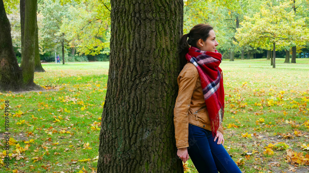Woman at a tree in a park in autumn. Woman at a tree in a park in autumn.