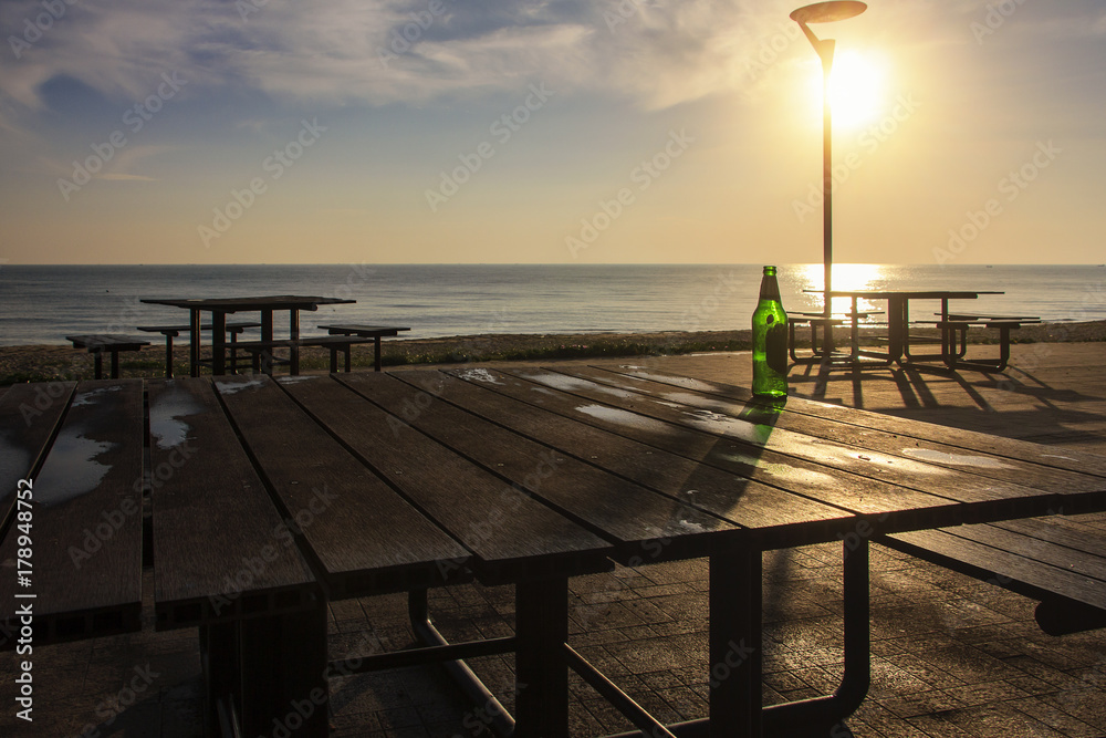 old beer bottle on wooden table near beach