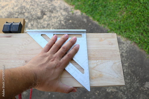 Hand of carpenter is measuring angle of wooden furniture
