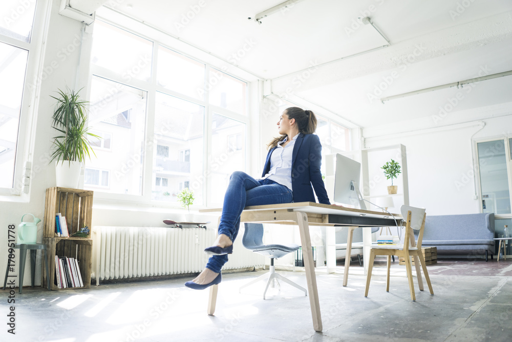 Businesswoman sitting on table in a loft Businesswoman sitting on table in a loft