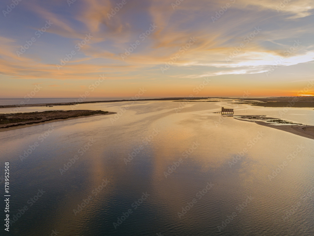 Aerial sunset and historic life-guard building at Fuseta fishing town, in Ria Formosa wetlands nature conservation park, Algarve. Portugal.