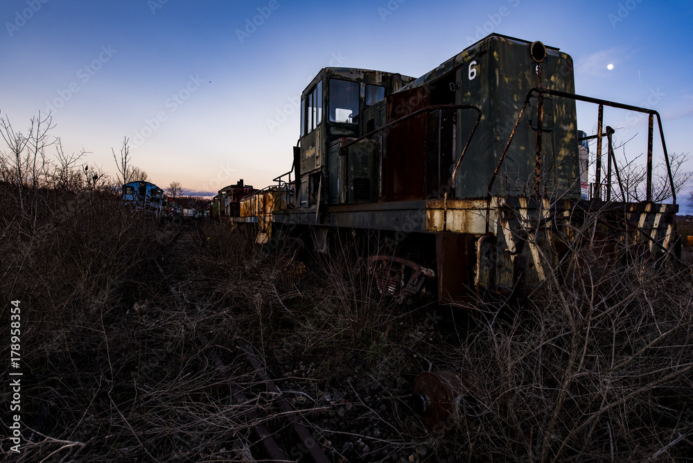 Fototapeta premium Derelict Locomotive at Twilight - Abandoned Railroad Trains
