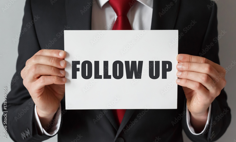 Businessman holding a card with text FOLLOW UP Businessman holding a card with text FOLLOW UP
