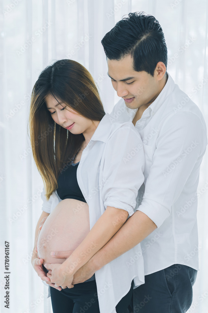 Beautiful pregnant woman and her handsome husband hugging and smiling Beautiful pregnant woman and her handsome husband hugging and smiling