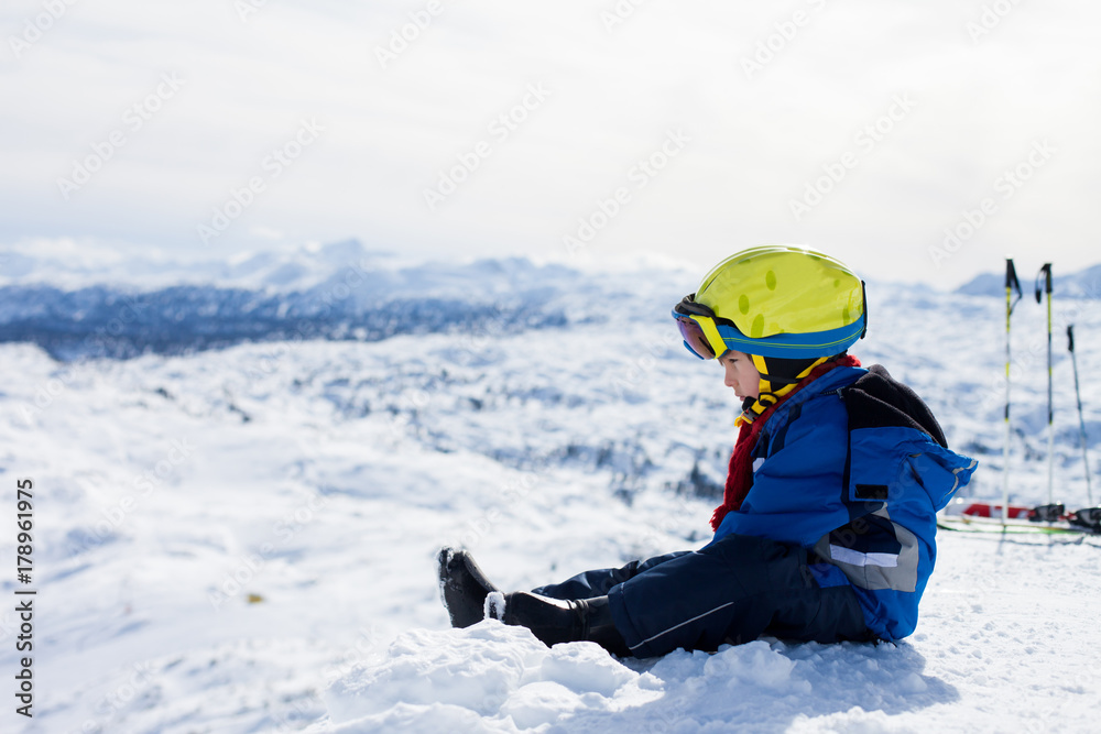 Cute little boy, skiing happily in Austrian ski resort in the mountains