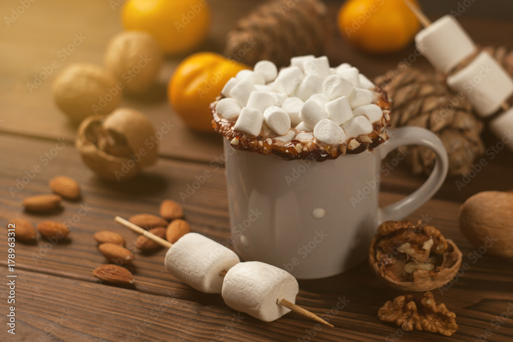mug with hot chocolate served with chunks of mandarins, nuts, marshmallow, cones, cinnamon on old wooden table mug with hot chocolate served with chunks of mandarins, nuts, marshmallow, cones, cinnamon on old wooden table
