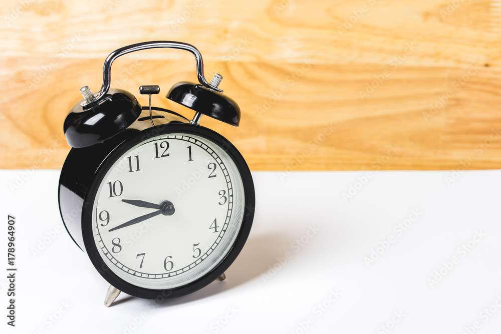 alarm clock on white table and wood wall