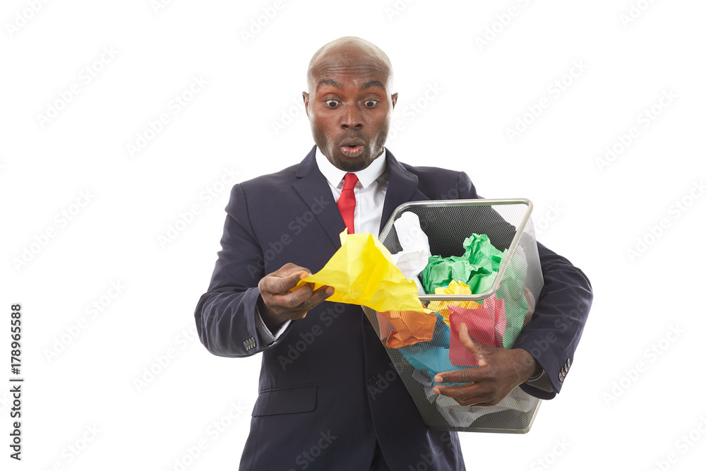 Portrait of African businessman searching document among crumpled papers in paper basket Portrait of African businessman searching document among crumpled papers in paper basket