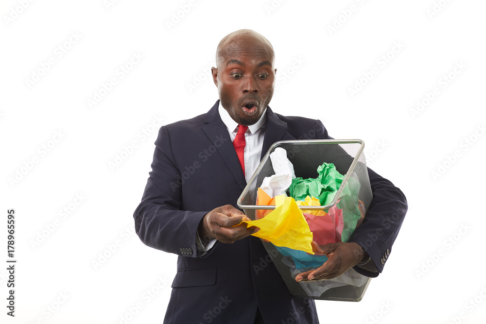 Portrait of African businessman searching document among crumpled papers in paper basket