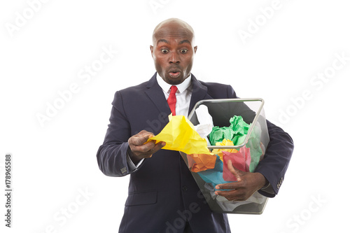 Portrait of African businessman searching document among crumpled papers in paper basket