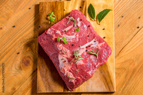Tender beef sirloin on wooden board with pepper, bay leaf and other spices on rustic wooden table. Selective focus