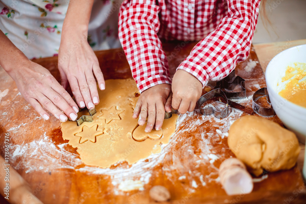 Merry Christmas and Happy Holidays. Family preparation holiday food. Mother and daughter cooking cookies in New Year interior with Christmas tree.