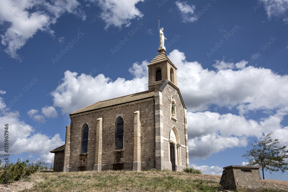 France, near Fleurie: Small old French chapel (Chapelle de la Madone) on top of a vineyard with blue sky in the background.