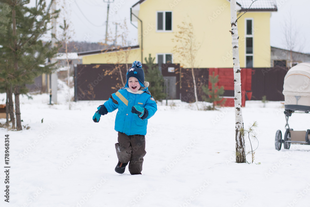 Happy boy running at a winter cottage village, Russia
