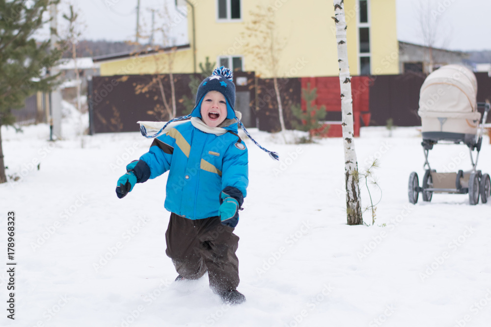 Happy boy running at a winter cottage village, Russia