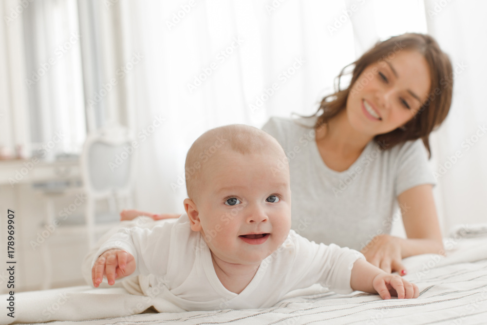 Mother and baby playing and smiling on the bed happy family. Boy looking at camera Mother and baby playing and smiling on the bed happy family. Boy looking at camera
