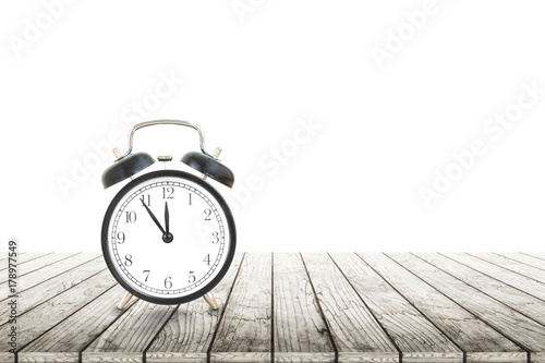 Alarm clock with 5 min before 12 o`clock on empty old wood table with white background.