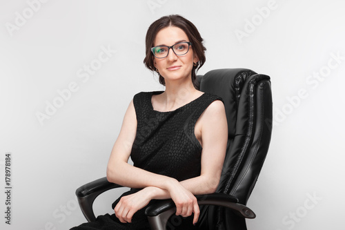 Picture of beautiful woman in black dress sitting on a armchair