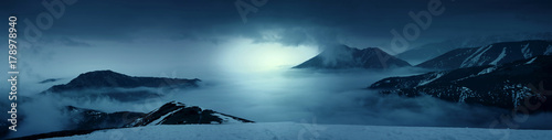Plakat Fantazi fotografia góry w mgle przy wieczór. Białe światła. Magiczne i malownicze pejzażowe zdjęcie