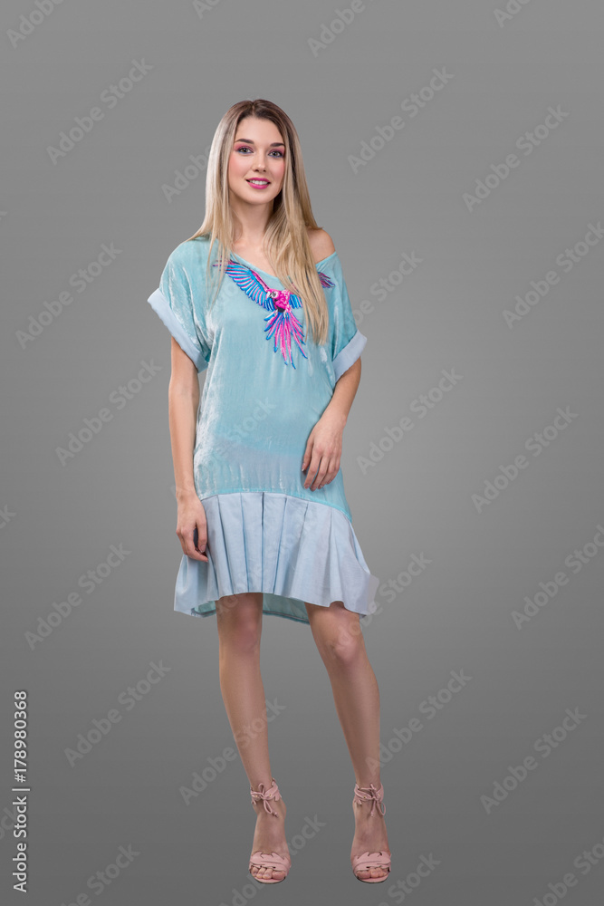 beauty, fashion and happy people concept - young woman in blue dress with a parrot and high heels over grey background beauty, fashion and happy people concept - young woman in blue dress with a parrot and high heels over grey background
