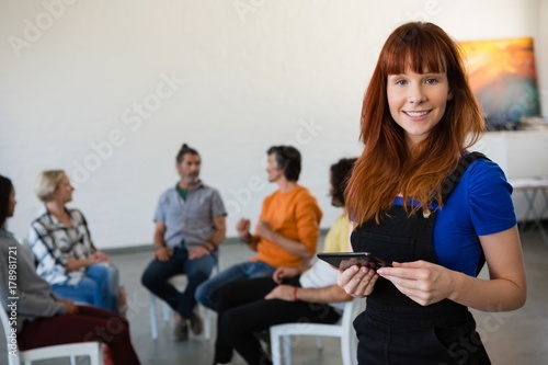 Portrait of happy teacher holding digital tablet with students