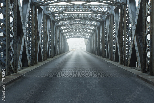 Metal construction of the city bridge on a foggy day in Dieppe, France. Empty asphalt road in the tunnel. Urban scene, city life, transport and traffic concept. Toned