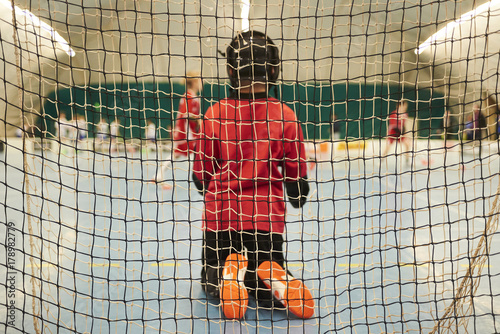 Unidentifiable floorball goalkeeper during mach. Child boy player scoring during the floorball match. Children playing floorball