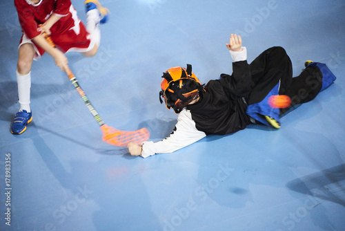 Unidentifiable floorball goalkeeper during mach. Child boy player scoring during the floorball match. Children playing floorball photo