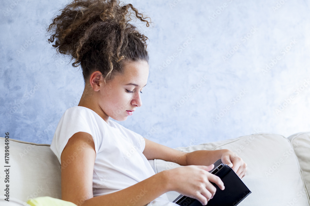 Fototapeta premium Curly hair girl using digital tablet on sofa