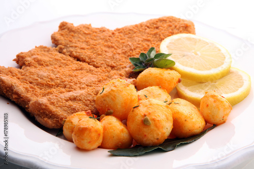 Golden schnitzel, boiled potatoes and lemon on a plate.