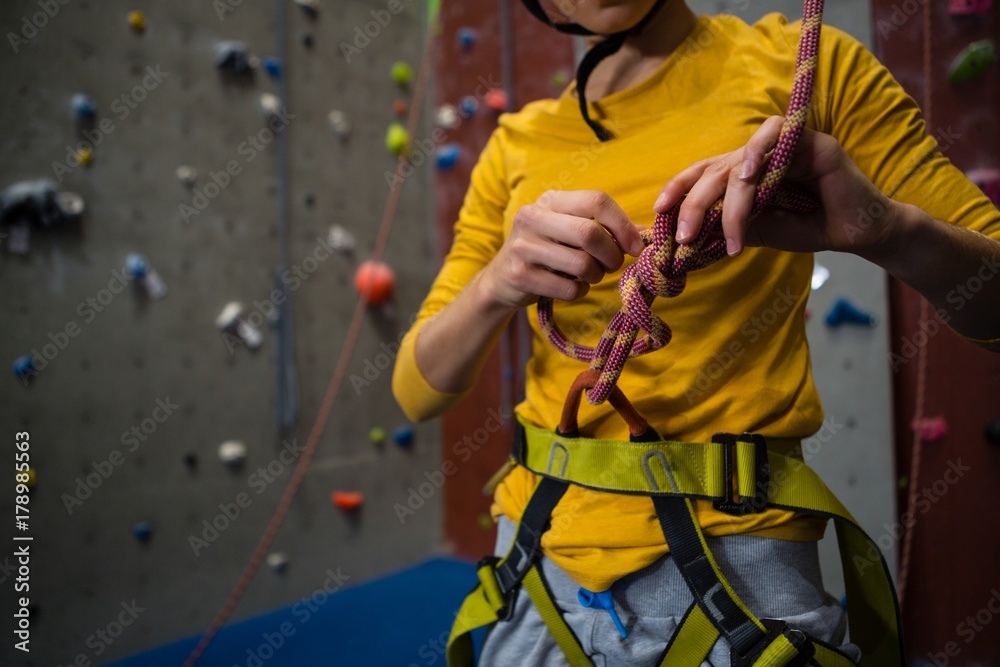 Midsection of female athlete tying rope in health club