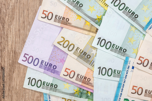 mant euro bills on wooden desk. close up