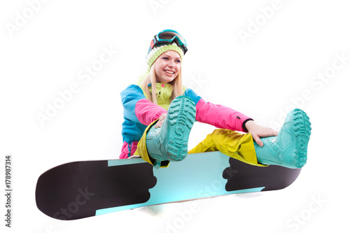 attractive young woman in ski suit and ski glasses sit on snowboard