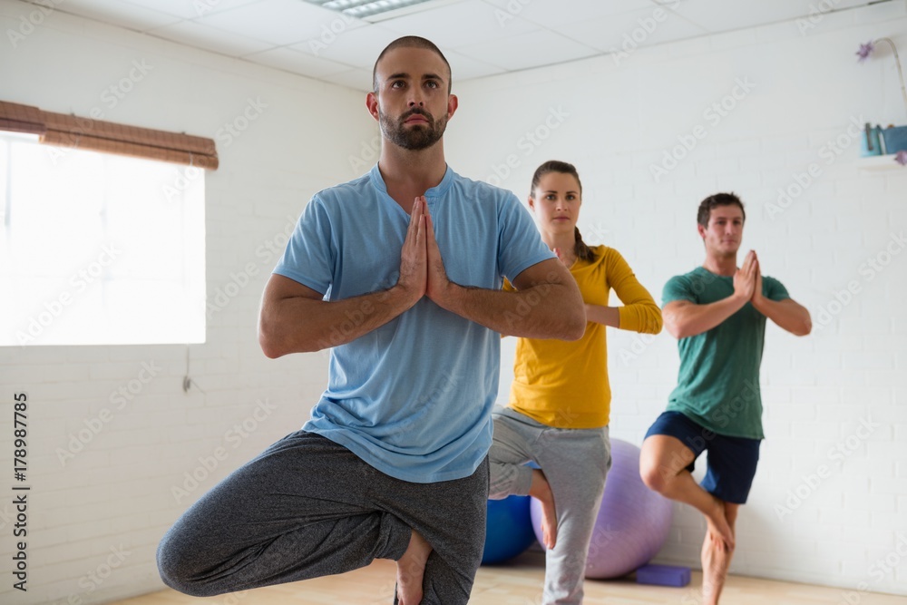 Fototapeta premium Instructor with students practicing tree pose in health club