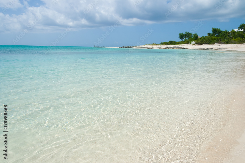 Turquoise sea water with white sand beach and blue sky. Turks and Caicos Islands.
