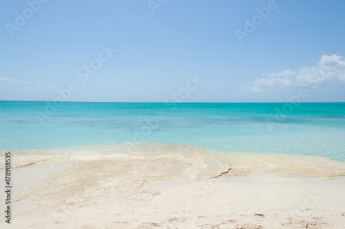 Turquoise sea water with white sand  rock beach and blue sky. Horizon line  Turks and Caicos Islands.