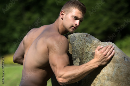 Man bodybuilder with muscular torso, biceps, triceps push stone © Volodymyr