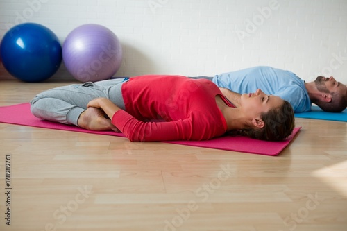 Instructor with student practicing reclined hero pose in studio