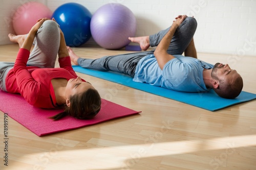 Yoga instructor and student exercising while lying on mat in