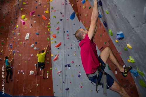 Confident athletes and trainer climbing wall in club