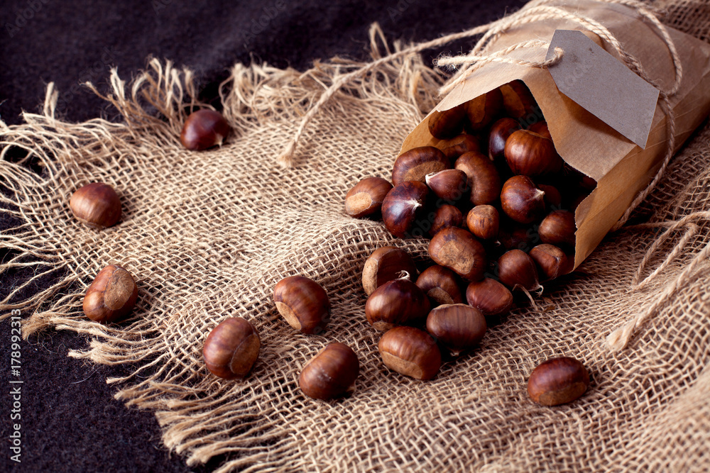 edible chestnuts - a bag of fresh, raw chestnuts sprinkled on the table