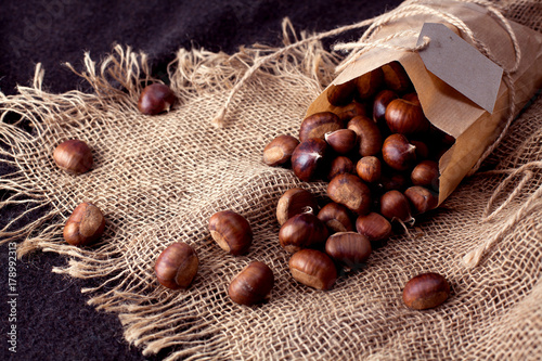 Obraz na płótnie edible chestnuts - a bag of fresh, raw chestnuts sprinkled on the table w salonie
